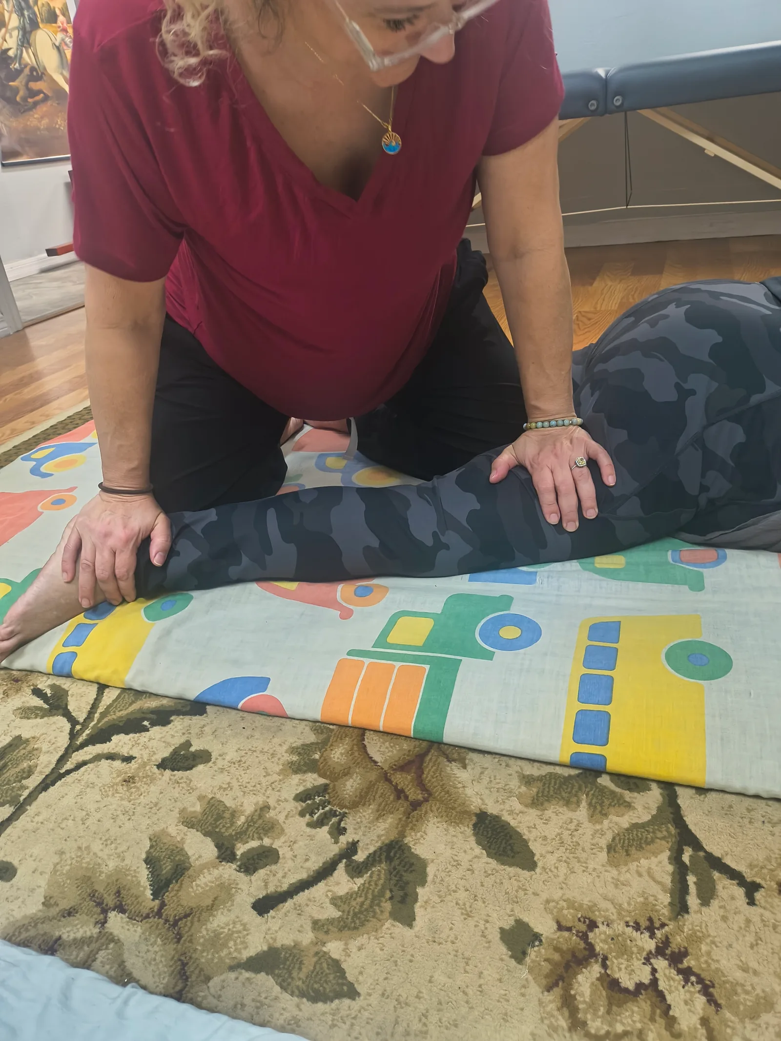 Hands-on supported leg stretch during the SomaVeda class